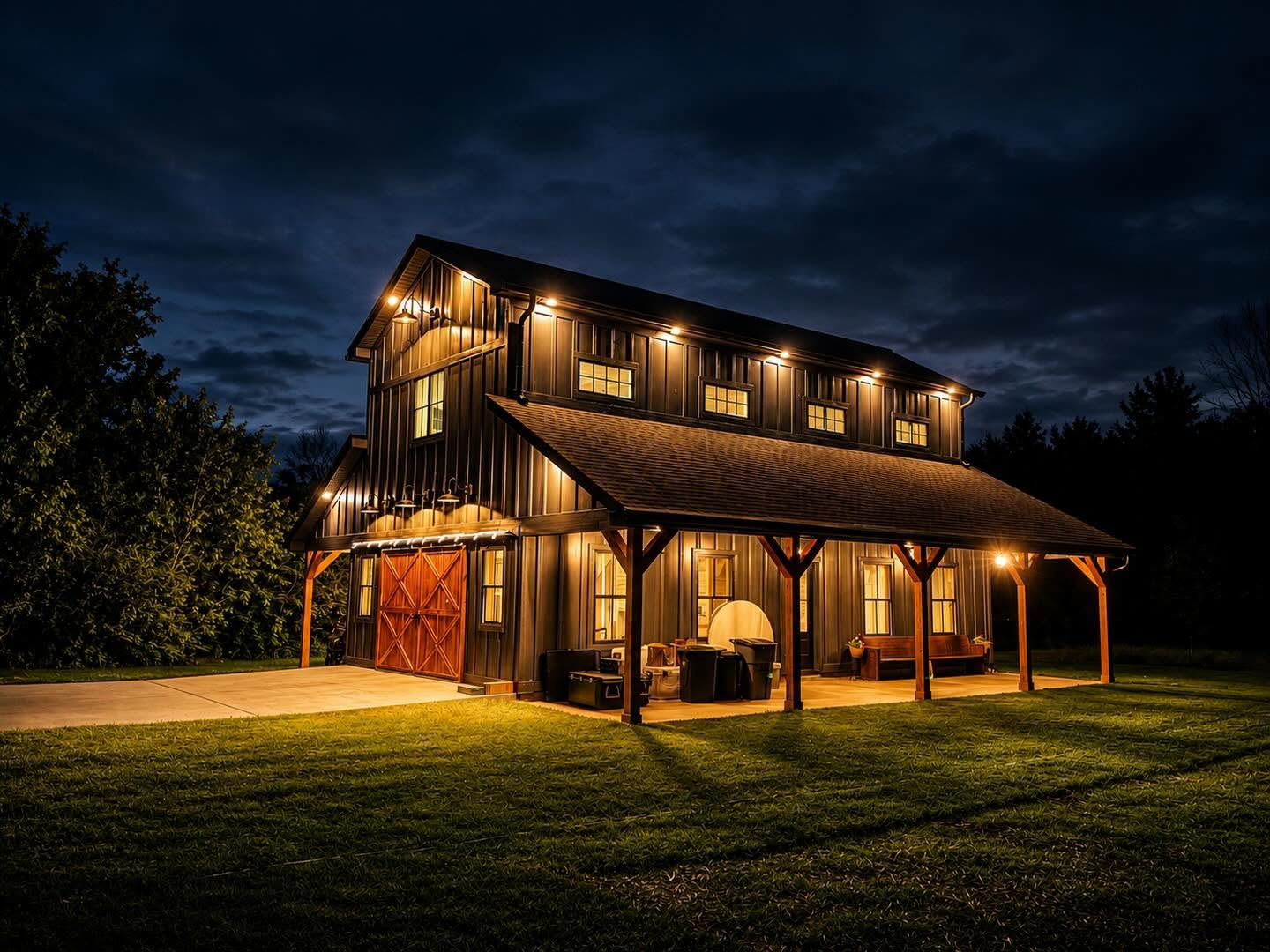 Charcoal barn with timber porch posts and warm exterior lights after dark