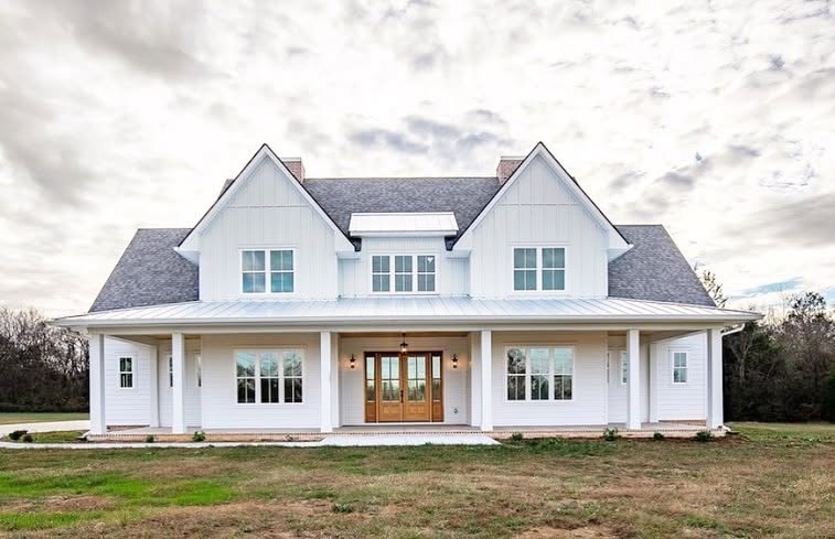 White farmhouse with two front gables, a central dormer and a covered front porch
