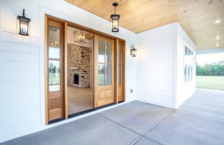 Open timber front door and white siding at the farmhouse entrance