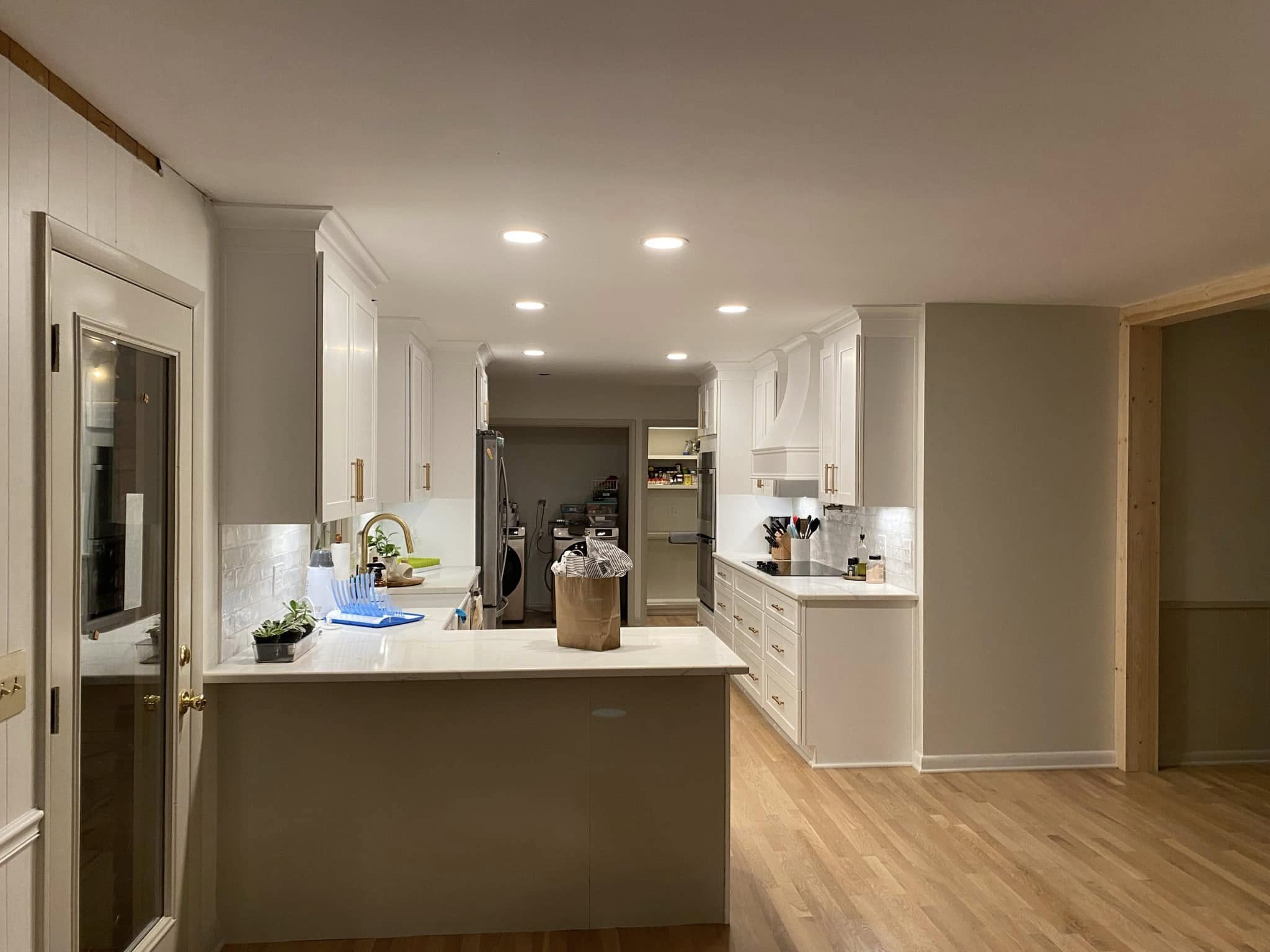 Renovated kitchen with white cabinetry, a peninsula and wood flooring