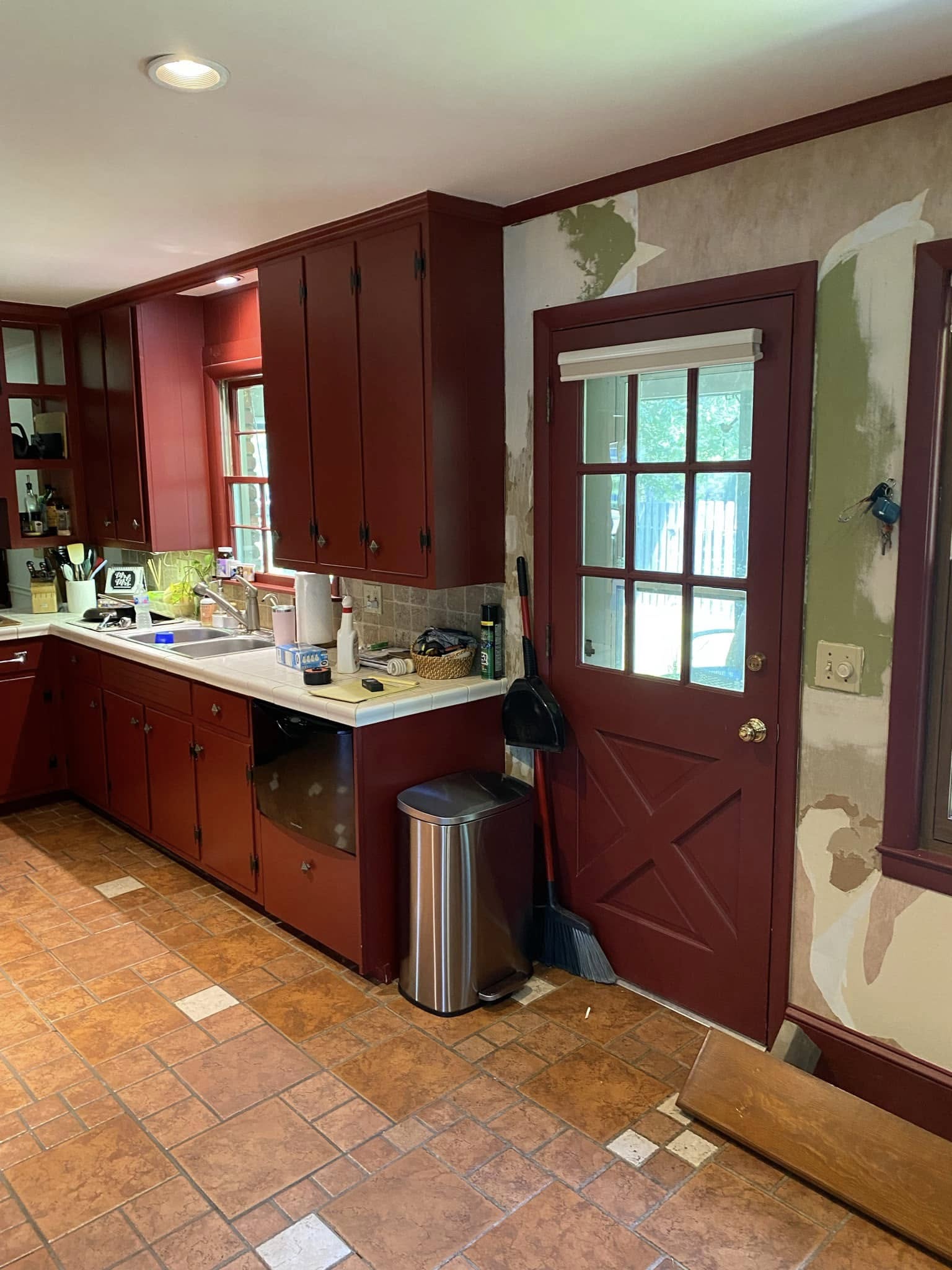 Kitchen before renovation with red cabinets and trim and tile flooring