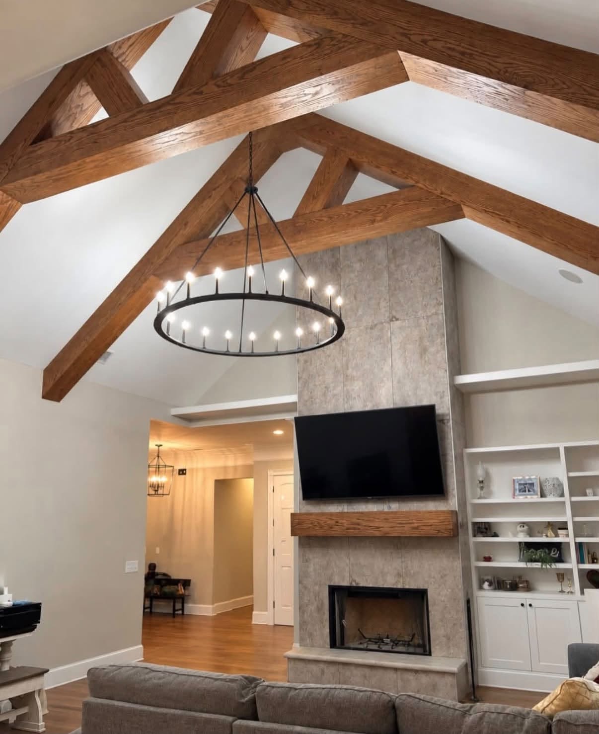 Renovated living room with heavy timber trusses, a tall fireplace and white built-ins
